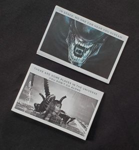 Two zine covers at an angle, showing aliens from the first and second ALIEN movies