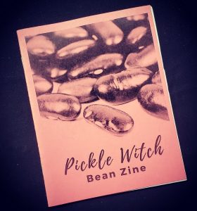 black background with a pink zine cover that has a photograph of beans on it