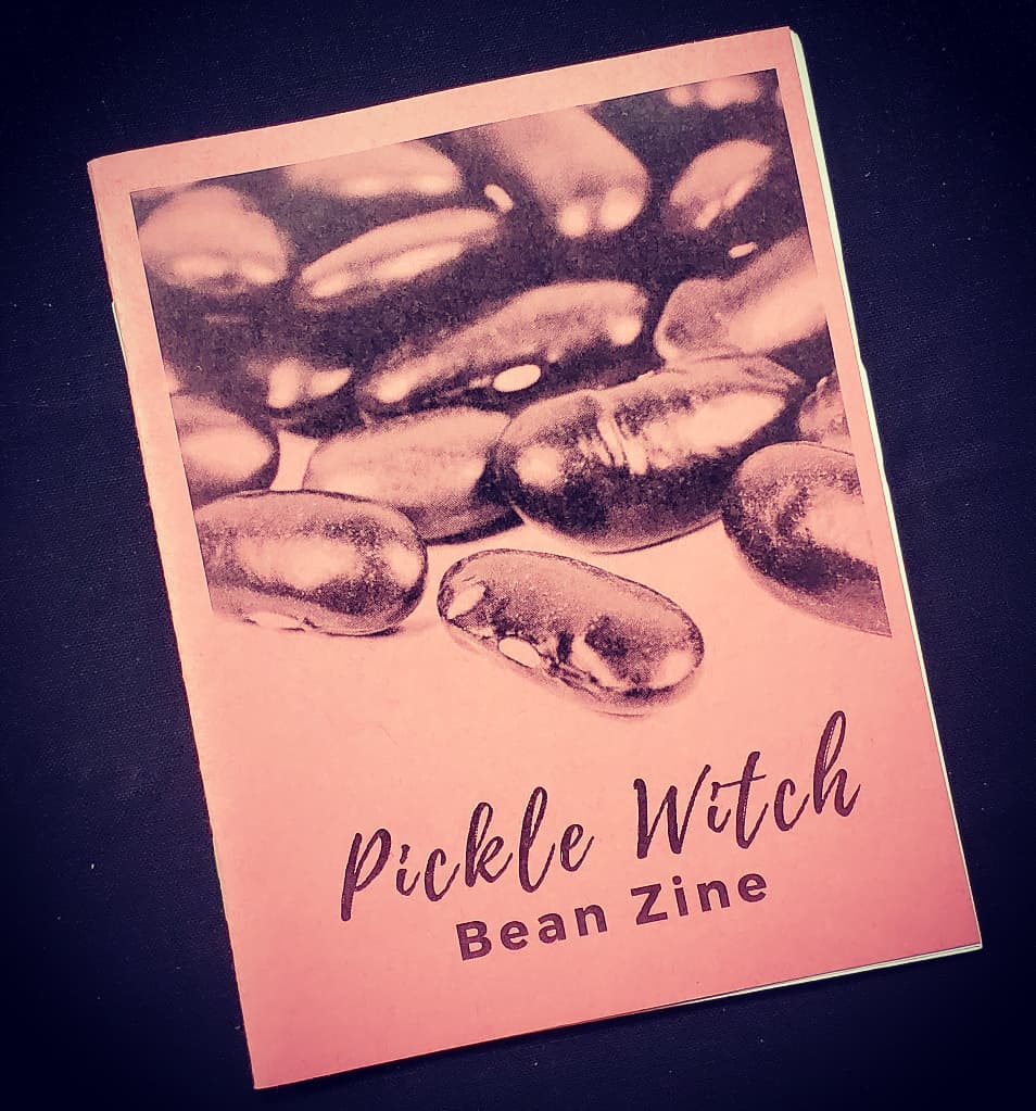 black background with a pink zine cover that has a photograph of beans on it