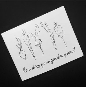 black background with a white zine which shows black and white line drawings of vegetables, and the text, "how does your garden grow?"
